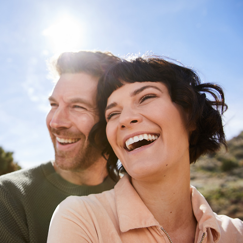 Young man hugging his laughing wife from behind