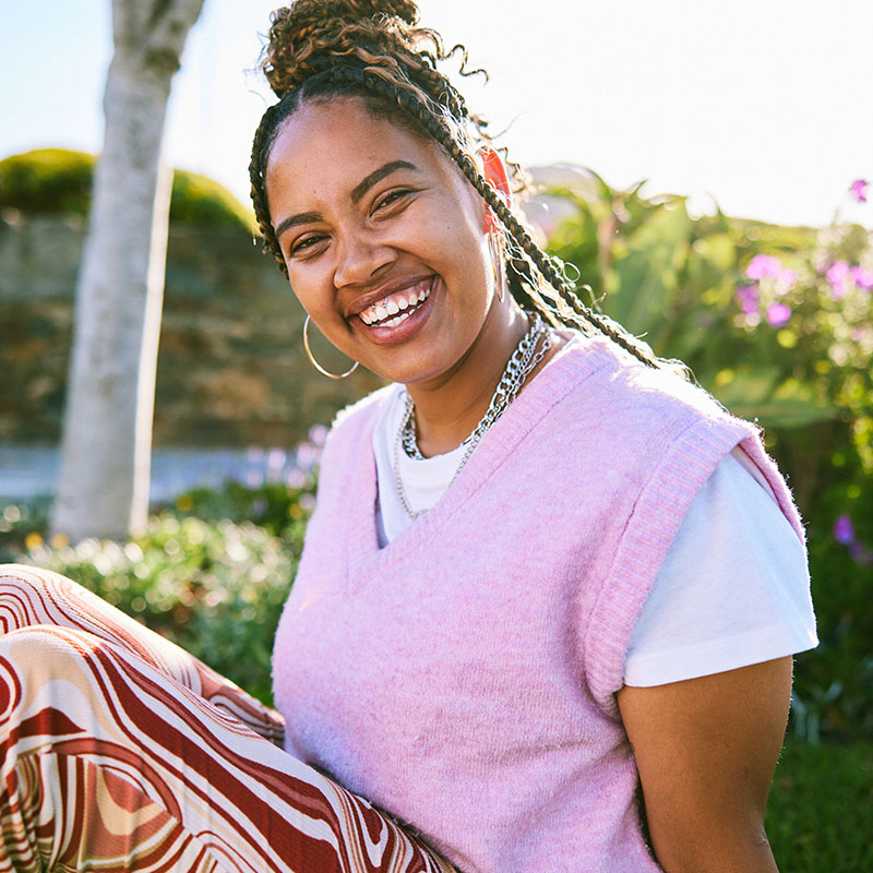 Cheerful young woman with braided hair smiling towards camera
