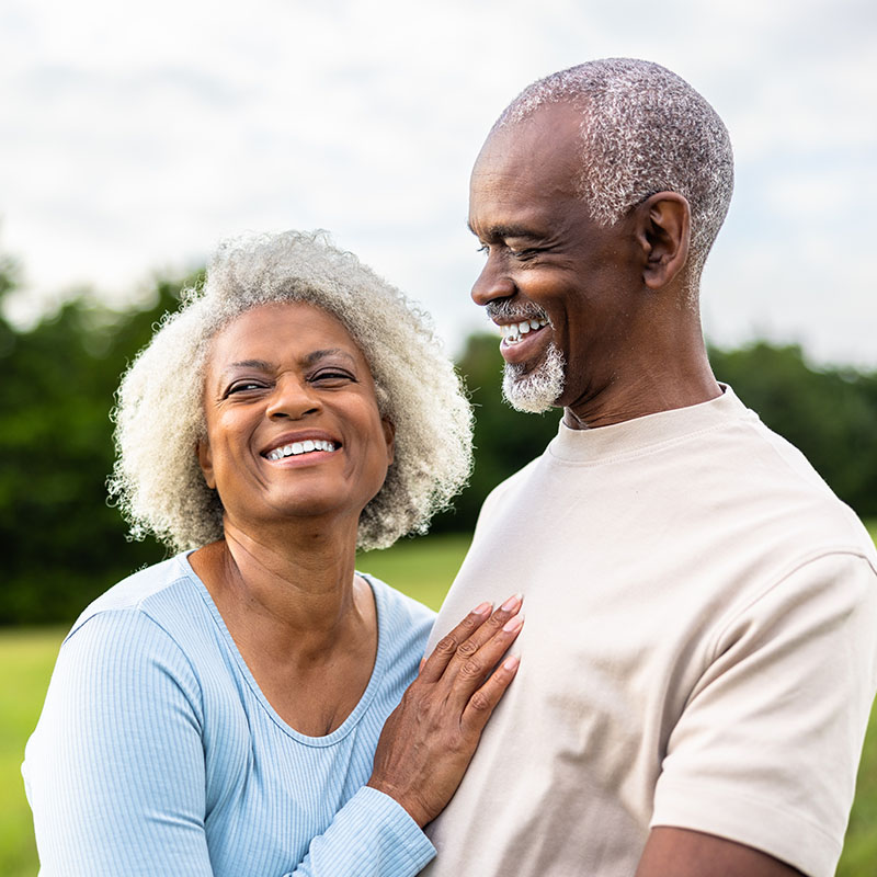 Senior black couple laughing together during exercise outdoors in field