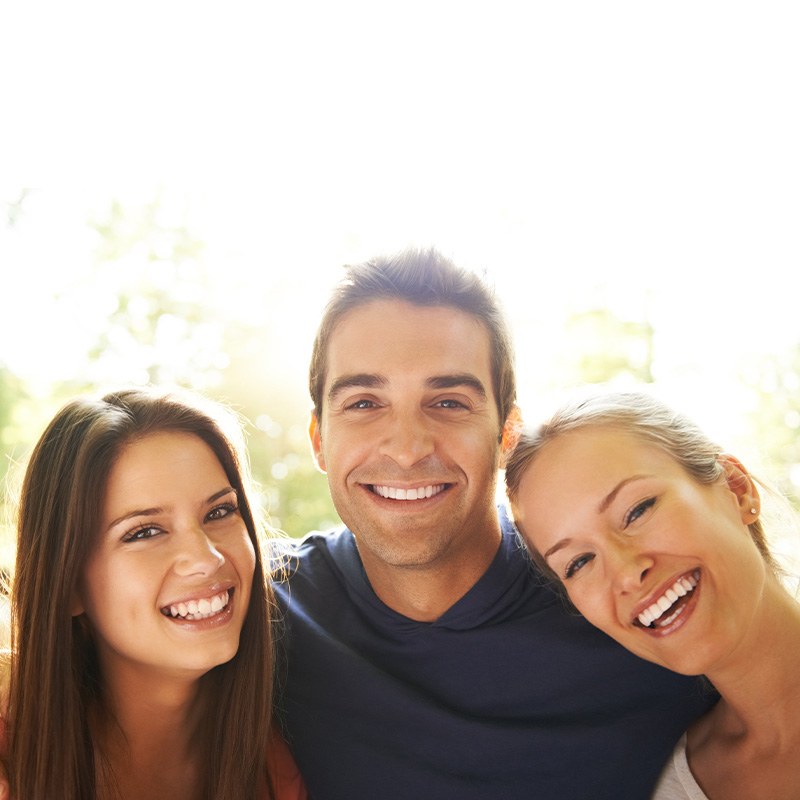 Three young friends embracing one another while enjoying a day out in nature