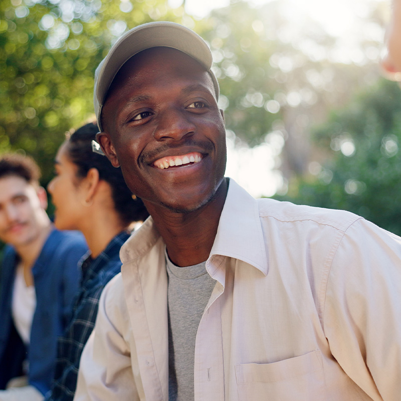 man smiling outside sitting with friends